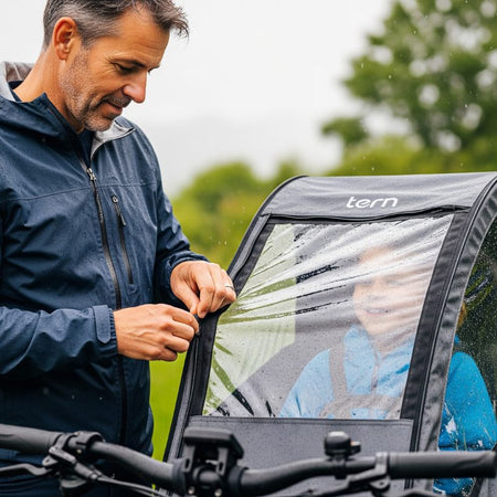 A father demonstrating the easy to use zipper on an all weather child bike seat rain cover.