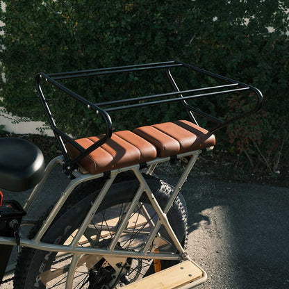 Brown Murf Cargo Seat Pad accessory installed on the extended rear cargo rack of a light-colored e-bike, featuring the Cargo Carriage installed